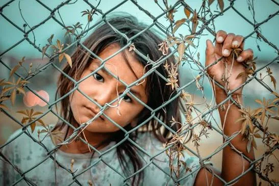 Child standing behind a fence