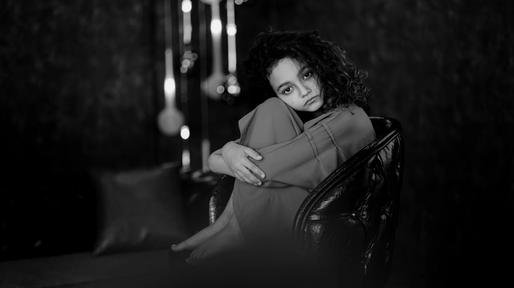 Child seated in a reflective black-and-white portrait